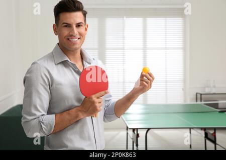 Geschäftsmann mit Tennisschläger und Ball in der Nähe des Tischtennistisches im Büro. Platz für Text Stockfoto