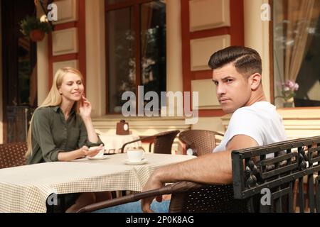 Ein Mann hat ein langweiliges Date mit einer gesprächigen Frau im Café draußen Stockfoto