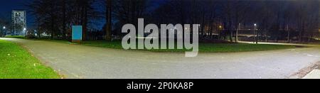 Panoramablick auf einen leeren Park bei Nacht mit Lichtern eines Fahrradweges im Hintergrund, ohne dass jemand im Park ist Stockfoto