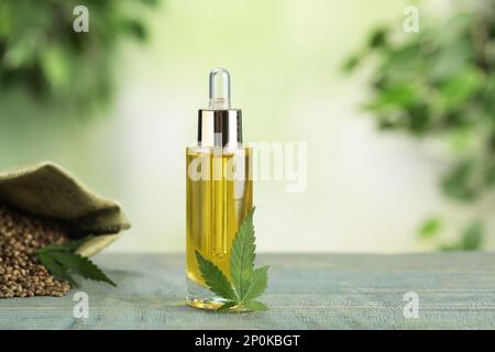 Hanföl und Blatt auf Holztisch vor unscharfem Hintergrund. Platz für Text Stockfoto