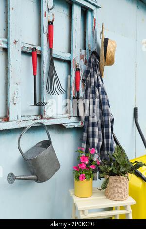 Schöne Pflanzen, Gartenwerkzeuge und Zubehör in der Nähe von Metallwänden Stockfoto