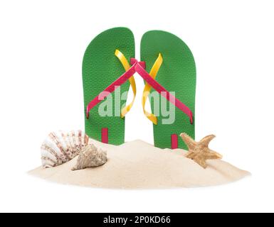 Grüne Flip Flops in Sand, Seesternen und Muscheln auf weißem Hintergrund Stockfoto