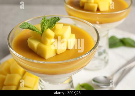 Köstliches Panna Cotta mit Mango-Coulis, frischen Obststücken und Minze in der Dessertschüssel, Nahaufnahme Stockfoto