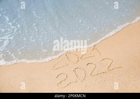 Datumsangaben stehen auf Sandstrand. 2021 von Meereswelle gewaschen als neues 2022. Jahr kommt Stockfoto