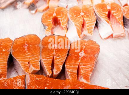 Nahaufnahme von Steaks aus rotem Fischlachs und Forellen mit Eis auf der Theke. Verkauf Stockfoto