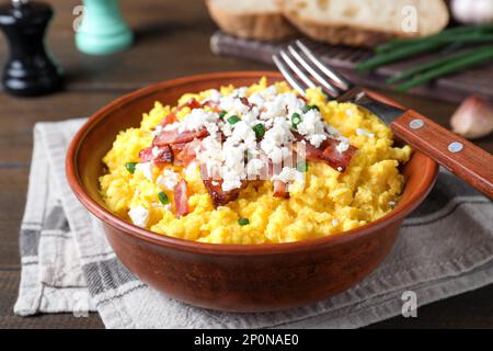 Leckerer Banosh serviert mit Brynza und Schweinegrieben in der Schüssel auf dem Tisch, Nahaufnahme. Traditionelles ukrainisches Gericht Stockfoto