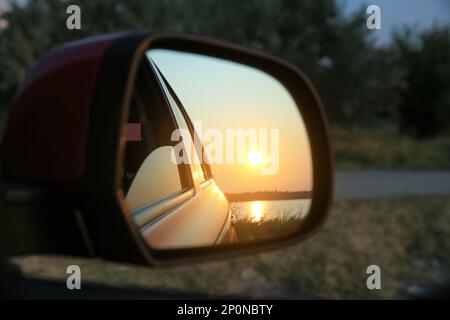 Reflexion der Landschaft mit wunderschönem Sonnenuntergang über dem ruhigen Fluss im Auto, Seitenspiegel, Nahaufnahme Stockfoto