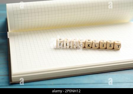 Holzwürfel mit Wort Blacklist und Notizbuch auf dem Tisch Stockfoto