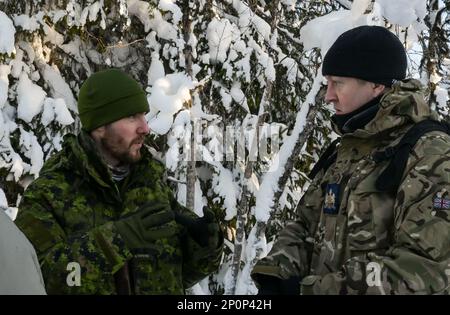 Der Royal Air Force Warrant Officer Simon Waldock, Kommandoleiter des alliierten NATO Air Command, spricht mit einem Spezialisten der Royal Canadian Air Force SERE, während er während eines nordischen regionalen CSEL-Engagements am 21. Januar 2023 in Rauland, Königreich Norwegen, den Winter Survival-Kurs der NATO-Aircrew besucht. Stockfoto