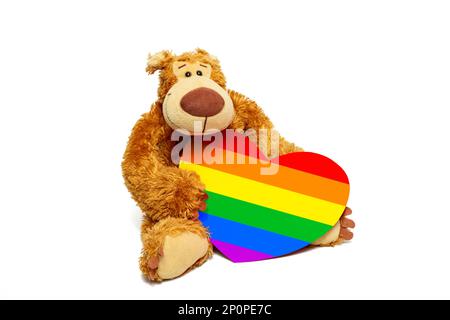 Teddybär mit einem regenbogenfarbenen Pappherz. Vorderansicht, Kopierbereich. Stockfoto