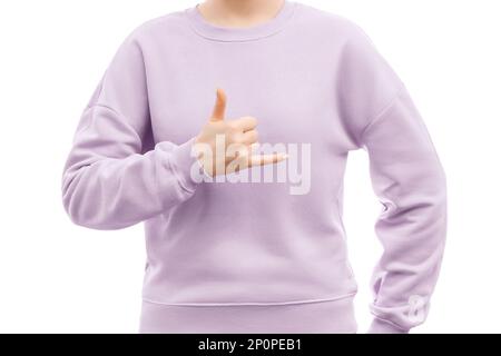 Auf dem Bild einer Frau in einem übergroßen, lavendelfarbenen Sweatshirt ist "Hang Loose shaka" -Schild zu sehen. Stockfoto