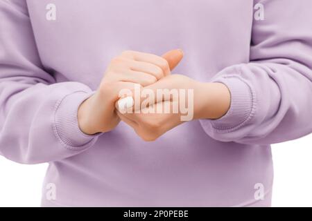 Gekürzte Aufnahme einer Frau in einem übergroßen, lavendelfarbenen Kapuzenpullover mit Handcreme. Stockfoto