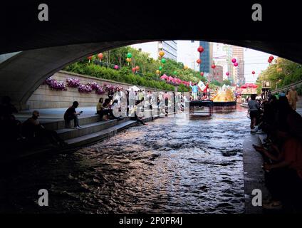 Seoul, Südkorea - 2019. Mai: Malerischer Blick auf den Cheonggye Stream (Cheonggyecheon) in der Innenstadt. Leute, die unter der Brücke am Fluss ruhen Stockfoto