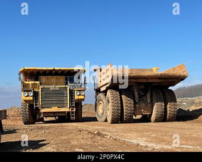 Dämpfer, die auf einer riesigen Bergbaustelle arbeiten, Dämpfer transportieren das Material. Stockfoto