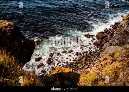 Wellen stürzen auf Felsen unter den Klippen auf Westman Island, Südinsel Stockfoto