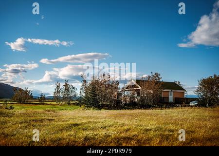 Abgelegenes Chalet in Island mit Berg im Hintergrund und blauem Himmel Stockfoto