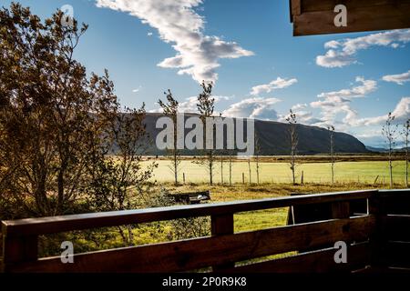 Blick vom Balkon mit Terrasse über flaches Grasland auf die Bergkette in der südisländischen Gegend von Selfoss Stockfoto