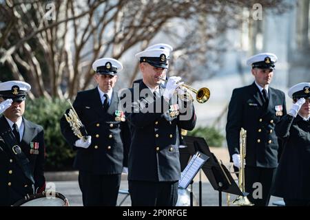 Ein Trompeter der Navy Band Ceremonial Brass Ensemble spielt "Taps" während einer Feier anlässlich des 125. Jahrestages des Untergangs der USS Maine, Arlington National Cemetery, Arlington, Virginia, am 15. Februar, 2023. Am 15. Februar 1898 explodierte die USS Maine vor der Küste von Havanna, Kuba, und 260 ihrer Crew gingen verloren. Aufgrund der spanischen Politik mussten die Beerdigungen innerhalb von 24 Stunden erfolgen, daher wurde die erste Besatzung, die nach der Katastrophe wieder aufgefunden wurde, auf dem Colon Friedhof in Havanna begraben. Am 30. März 1898 genehmigte der Kongress ein Gesetz, das die Desertation ihrer sterblichen Überreste autorisierte Stockfoto