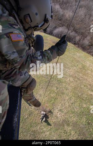 Sgt. 1. Klasse Jonas Chinea erhebt Sergeant 1. Klasse Anthony Bonillas, Kosovo Force (KFOR) Regional Command-East (RC-E) Soldaten mit der medizinischen Evakuierungseinheit, die Charlie Company zugewiesen wurde, 2. Bataillon, 149. Luftfahrtregiment, während sie am 6. Januar eine Hebeoperation von einem UH-60 Black Hawk Helikopter in Camp Bondsteel, Kosovo, durchgeführt haben. 2023. Stockfoto