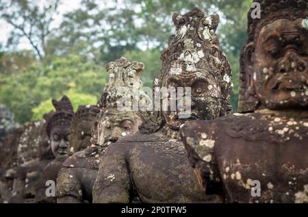 Riesige Steinköpfe säumen die Straße an einem Eingang zur berühmten Stadt Angkor Thom in Angkor, Siem Reap, Kambodscha. Stockfoto