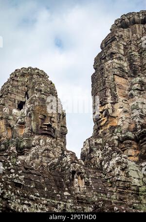 Auf den Türmen der Ruinen des berühmten Bayon-Tempels in der antiken Stadt Angkor Thom in Angkor Wat bei Siem sind riesige Steingesichter zu sehen Stockfoto