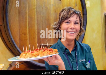 Eine Kellnerin hält einen Teller Pinchos in einer baskischen Bar in Barcelona, Spanien Stockfoto