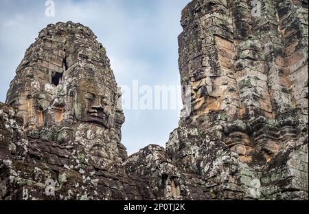 Auf den Türmen der Ruinen des berühmten Bayon-Tempels in der antiken Stadt Angkor Thom in Angkor Wat bei Siem sind riesige Steingesichter zu sehen Stockfoto