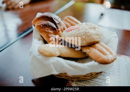 Ein Holztisch mit einem Korb voller Brot, fertig zum Servieren Stockfoto