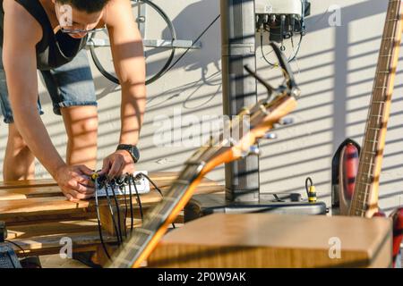 Junger lateiner, der Kabel in der Musik-Mixer-Steuerung anschließt, für Livemusik-Set, Musikproduktionskonzept, Musikkurse, Aufführungen, Konzerte, Instrume Stockfoto