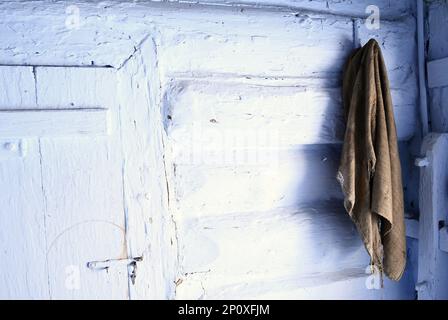 Ein alter Lappen, der an einer weißen Holzwand eines alten Cottage hing Stockfoto