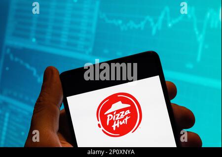 China. 15. Februar 2023. In dieser Fotoabbildung ist das Logo der amerikanischen Fast-Food-Pizza-Restaurantkette Pizza Hut auf einem Smartphone zu sehen, das im Hintergrund mit einem Index der Börse für die Wirtschaft versehen ist. Kredit: SOPA Images Limited/Alamy Live News Stockfoto