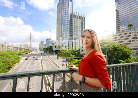 Reisen Sie in Sao Paulo, Brasilien. Porträt eines schönen lächelnden Mädchens mit Sao Paulo Stadtbild und Ponte Estaiada Brücke im Hintergrund, Sao Paulo, Brazi Stockfoto