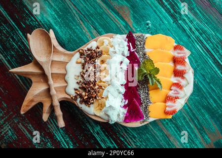 Smoothie-Schüssel in Ananasform, Früchte: Mango, Banane, Kokosnuss, Samen. Gesundes, tropisches Frühstück Stockfoto