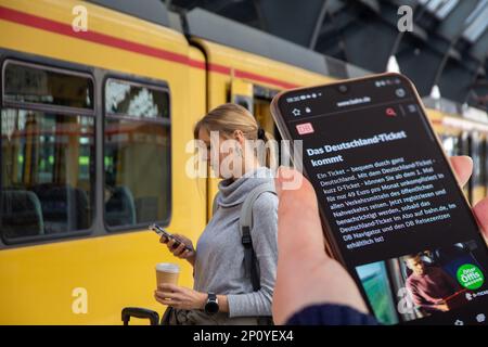 Symbol Bild Deutschlandticket, 49-Euro-Ticket: Nahaufnahme eines Smartphones vor einem Regionalzug (komponieren, Modell freigegeben) Stockfoto