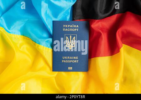 Die Flagge der Ukraine und Deutschlands in der Mitte liegt der biometrische ausländische Pass eines Ukrainers, migrieren Stockfoto