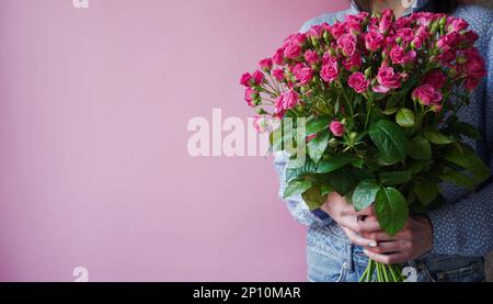 International Women's Day.Konzept des Grußbanners für den internationalen Frauentag am 8. März.Nahaufnahme Frauenhände mit großem Blumenstrauß rosa Rosen o Stockfoto