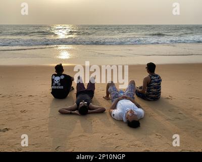 Candolim, Goa, Indien - Januar 2023: Vier junge indische Männer entspannen sich am Strand von Goa. Stockfoto