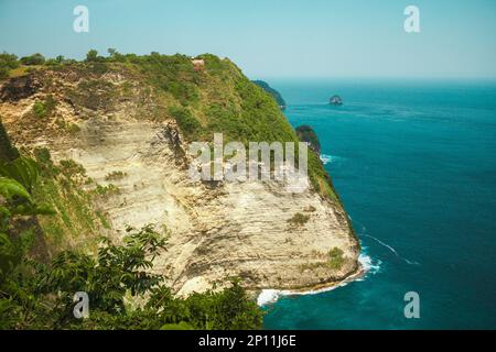 Der Strand von Atuh, die Insel Nusa Penida bei Bali, Indonesien. Meereswellen, Klippen mit tropischen Pflanzen Stockfoto