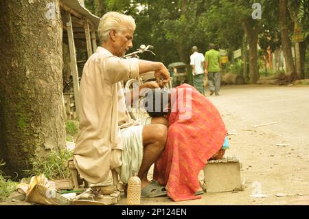 Bilder des provisorischen Friseurladens auf dem Land und verschmutzte Skulpturen und Ziegel in Bangladesch. Stockfoto