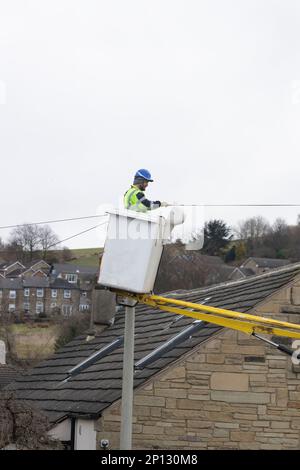 Telekommunikationsunternehmen mit entsprechender Sicherheitsausrüstung, das von einem Kirschpflücker aus arbeitet, um eine neue private Telefonleitung in West Yorkshire, Großbritannien, zu installieren Stockfoto
