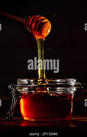 Honig mit einem natürlichen Holzstab auf schwarzem Hintergrund Stockfoto