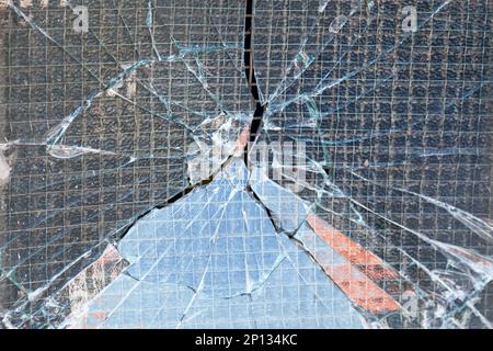 Nahaufnahme eines zerbrochenen verstärkten Glasfensters nach einem Vandalismus. Stockfoto