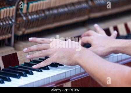 Nahaufnahme der Hand eines Pianisten, der auf einem aufrechten Klavier in der Fußgängerzone spielt. Stockfoto