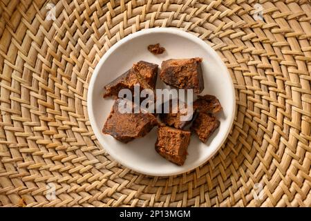 Kithul Jaggery und Treakel Natursüßer der Palme in weißer Schüssel auf traditionellem Weidenkorb. Blick von oben. Alternativer Zucker. Essen mit niedrigem GI-Wert. Super Stockfoto