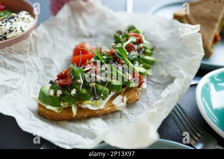 Gourmet-Avocado-Toast serviert mit getrockneten Tomaten und Mikro-Grüns zum Frühstück im Restaurant Stockfoto