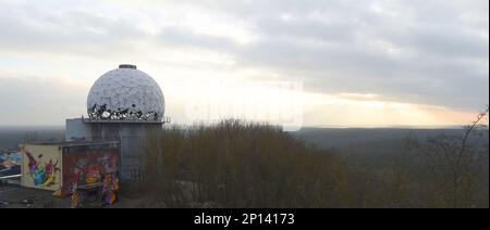 Berlin, Deutschland. 03. März 2023. Vom Berliner Teufelsberg aus geht die Sonne hinter dem Horizont unter bedeckten Himmel und kalten Temperaturen unter. Auf dem Berg befinden sich die markanten Gebäude einer Flugverkehrskontrollstation, deren Gebäude leer und veraltet sind und derzeit künstlerisch genutzt werden. Kredit: Felix Hörhager/dpa/Alamy Live News Stockfoto