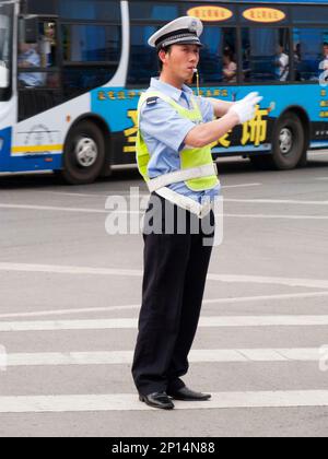 Polizeibeamter, Polizist, pfeift an einer verkehrsreichen Kreuzung in der chinesischen Stadt Xi'an. VR CHINA. China. Führen und Anweisen von vorbeifahrenden Fahrzeugen. (125) Stockfoto