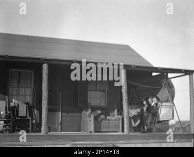 Arnold Genthe und zwei Freundinnen sitzen auf einer Schaukel auf der Veranda seines Bungalows in Long Beach, New York, zwischen 1911 und 1942 Uhr. Stockfoto