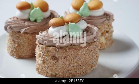 Mit cremefarbenen Blumen und Pilzen dekorierte Kekskuchen Stockfoto