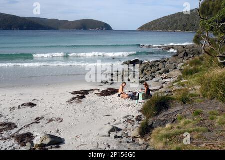 Der Strand an der Fortescue Bay Tasman Halbinsel, 2 Personen entspannen sich an der Küste in wunderschöner Umgebung Stockfoto